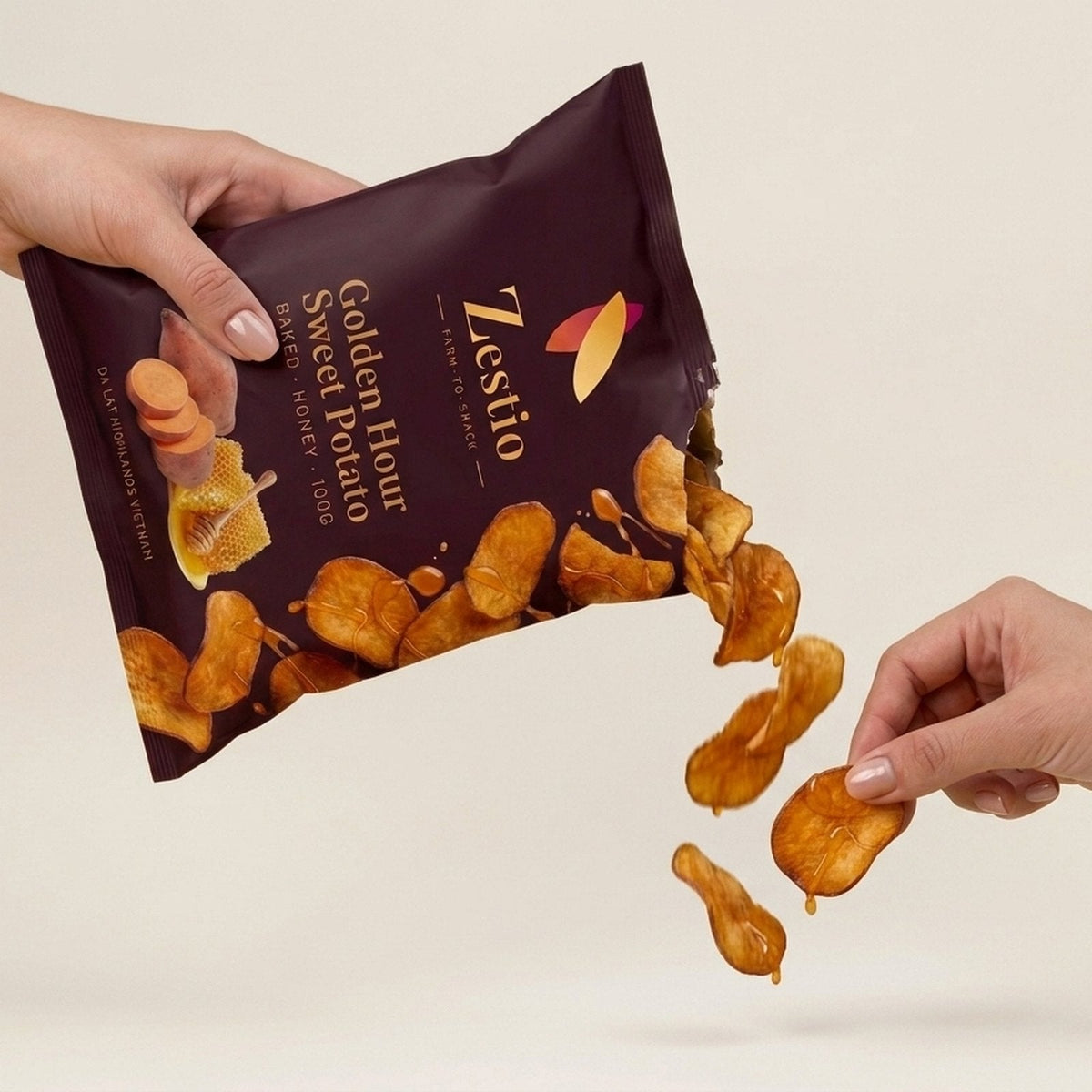 Hand holding a Golden Hour Sweet Potato chip, showing snack size and crisp texture