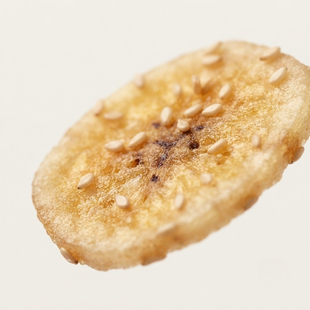 Close-up of a single Ginger Sesame Banana chip topped with toasted sesame seeds