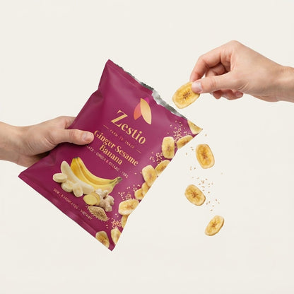 Hands holding the Ginger Sesame Banana pack and taking a chip, showing snack size