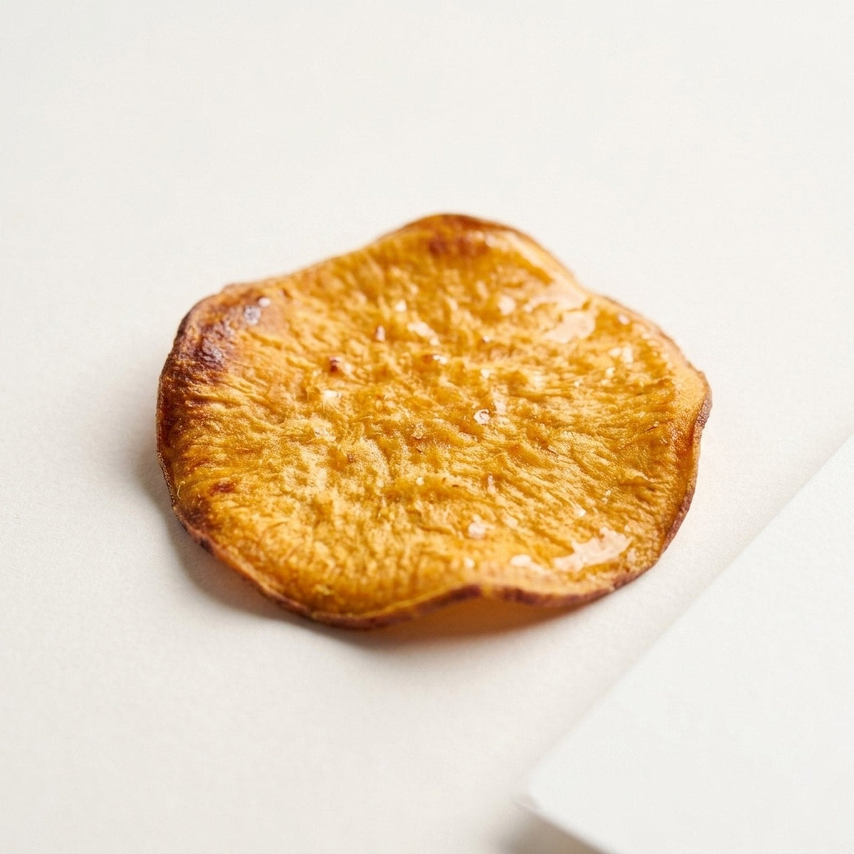 Close-up of a single Golden Hour sweet potato chip, honey glazed, baked never fried