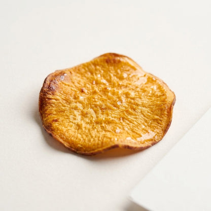 Close-up of a single Golden Hour sweet potato chip, honey glazed, baked never fried