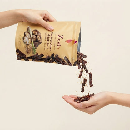 Hands pouring Smoke and Sesame Shiitake Jerky strips from the pack into an open palm