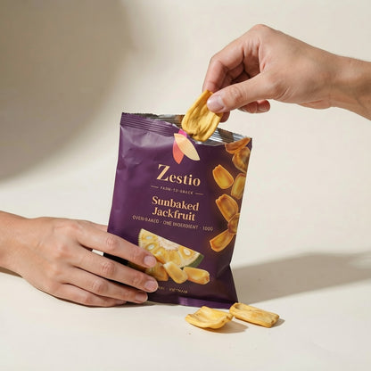 Hand taking a Sunbaked Jackfruit chip from the open pack, showing snack size